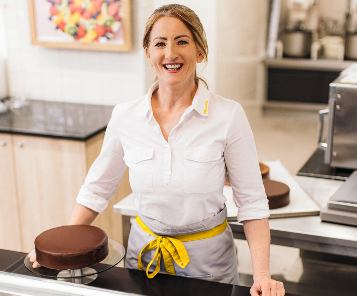 A smiling employee in front of a cake.