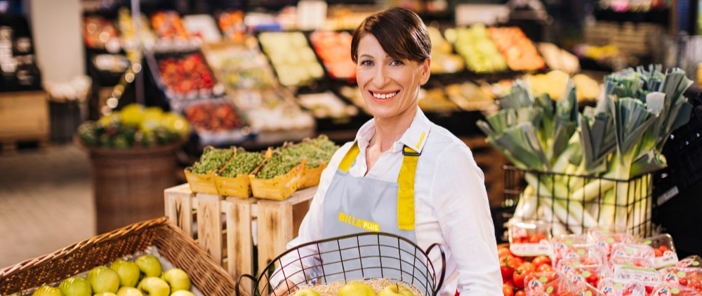 A smiling employee with a fruit basket.