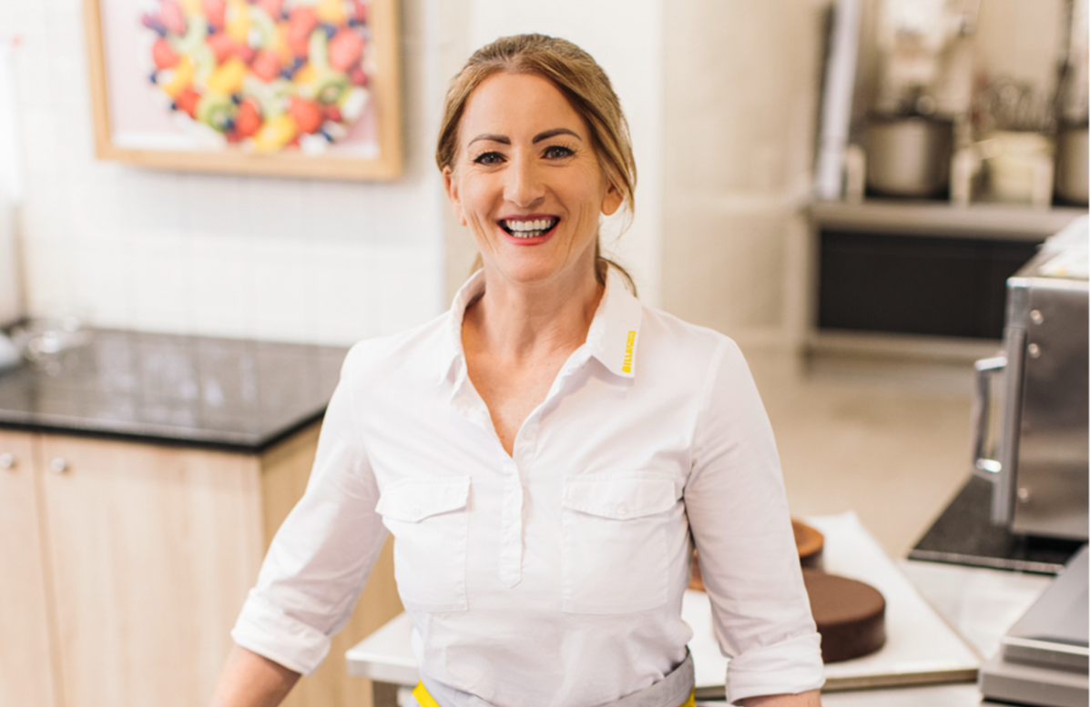 A smiling employee in front of a cake.