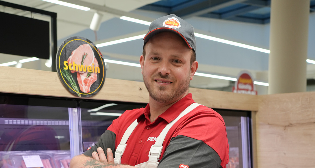 Ein Mitarbeiter schneidet ein Stück Fleisch.